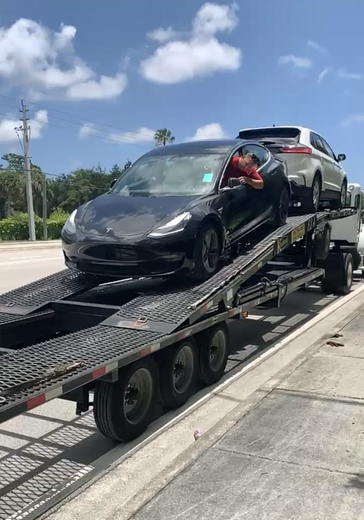 Black Tesla being transported on an open carrier trailer with Autos On The Go